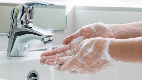 Person thoroughly washing their hands in the sink with soapy water. 